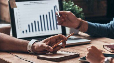 Plano de manos y port&aacute;til en mesa de oficina.